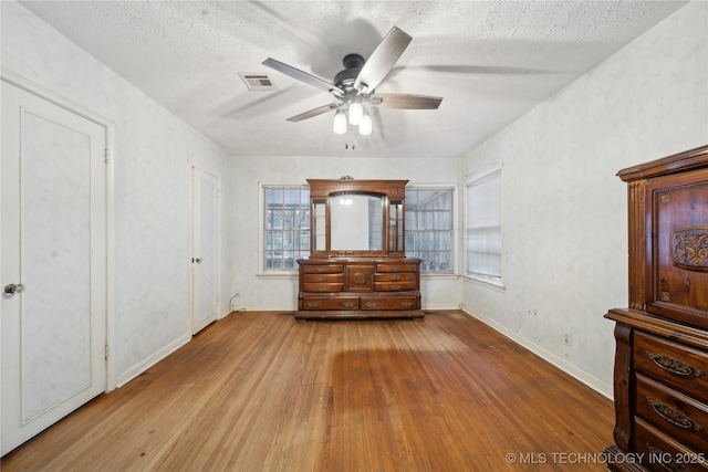 unfurnished bedroom featuring light wood-type flooring, ceiling fan, and a textured ceiling