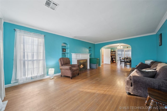 living room with a brick fireplace, plenty of natural light, ornamental molding, and hardwood / wood-style floors