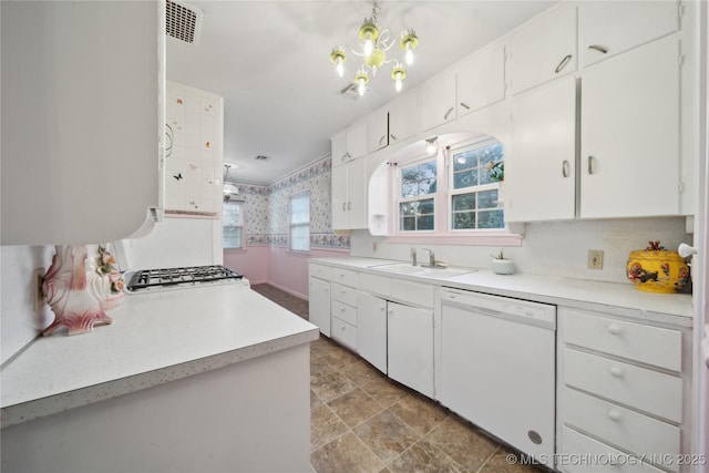 kitchen featuring pendant lighting, sink, white dishwasher, white cabinetry, and a chandelier