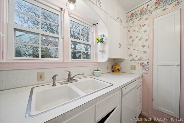 kitchen with sink, white dishwasher, and white cabinetry