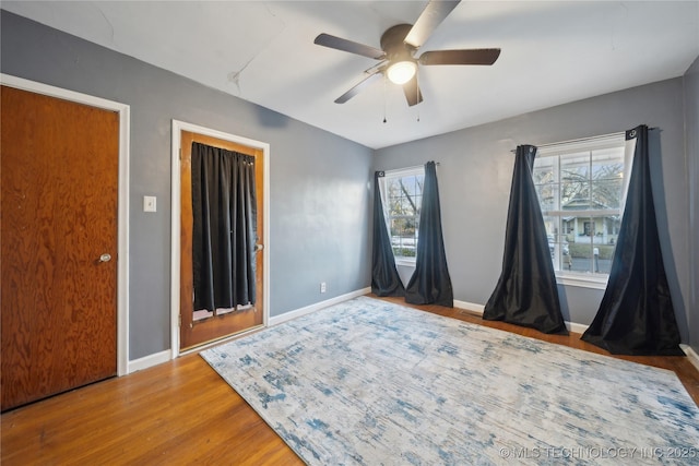 bedroom featuring ceiling fan, multiple windows, and hardwood / wood-style floors