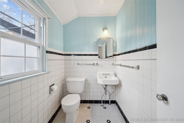 bathroom with toilet, tile walls, tile patterned floors, and ornamental molding