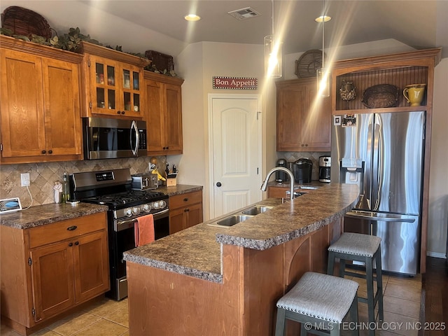 kitchen with tasteful backsplash, sink, an island with sink, a kitchen breakfast bar, and stainless steel appliances