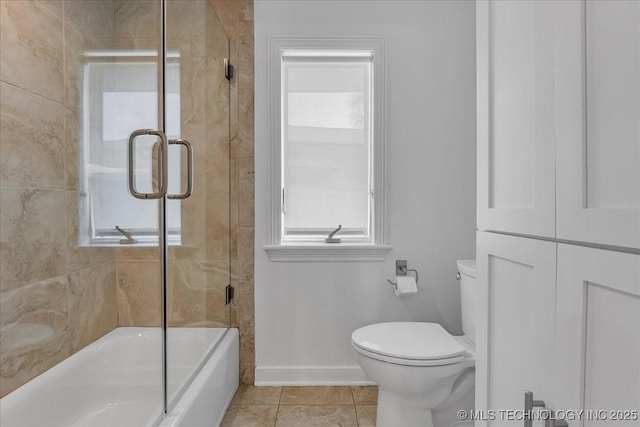 bathroom featuring toilet, tile patterned flooring, and combined bath / shower with glass door