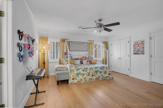 bedroom featuring ceiling fan, multiple windows, wood-type flooring, and ornamental molding