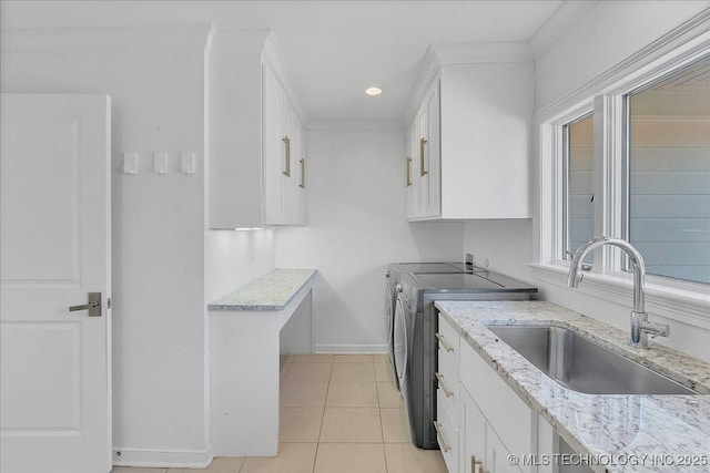 kitchen with light stone countertops, sink, white cabinets, and washer and clothes dryer