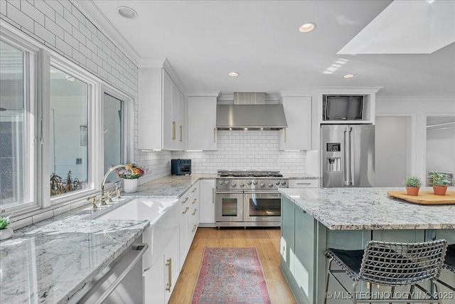 kitchen with tasteful backsplash, a breakfast bar, white cabinetry, high quality appliances, and light stone counters