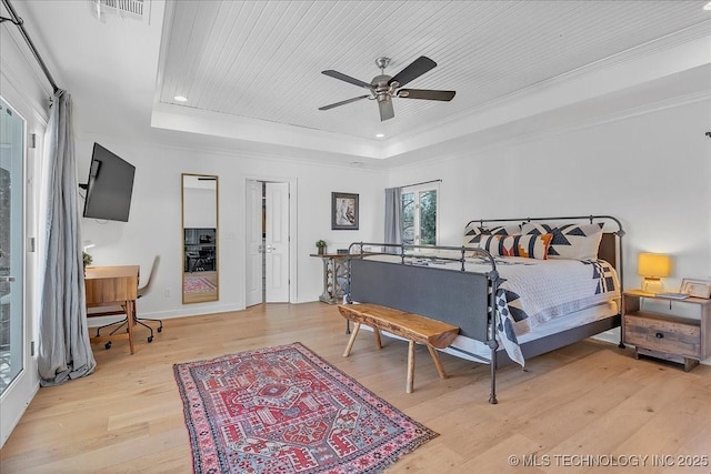 bedroom with light wood-type flooring, ceiling fan, and a raised ceiling