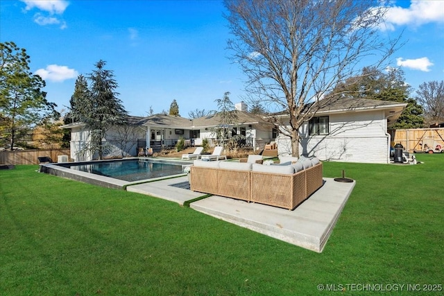 rear view of house with a patio area, outdoor lounge area, a fenced in pool, and a lawn