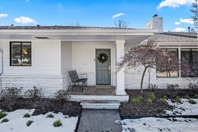 snow covered property entrance with a porch