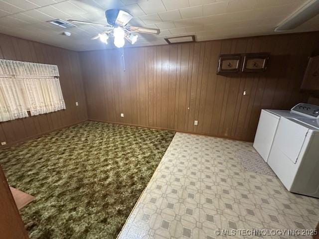 clothes washing area featuring ceiling fan, separate washer and dryer, and wood walls