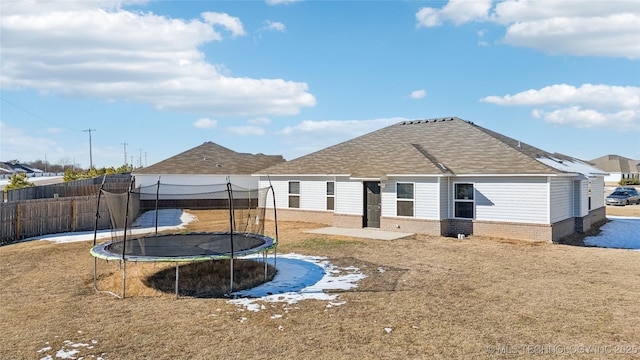 back of house featuring a yard and a trampoline