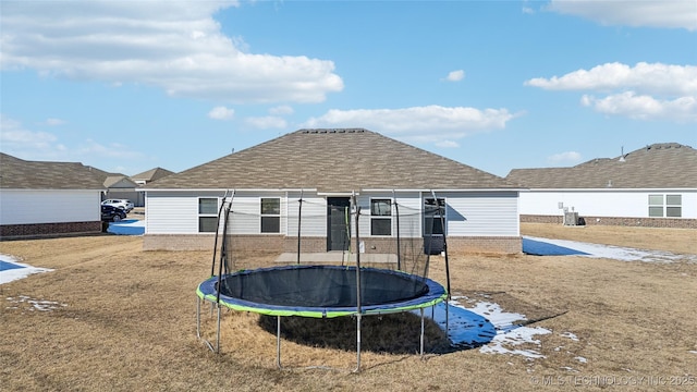 back of house featuring a trampoline and a yard