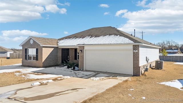 ranch-style home featuring central AC unit and a garage