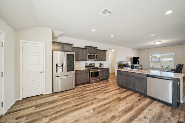 kitchen with a center island with sink, wood-type flooring, sink, dark brown cabinetry, and stainless steel appliances