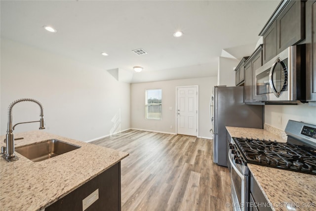 kitchen featuring light stone counters, sink, hardwood / wood-style floors, and appliances with stainless steel finishes