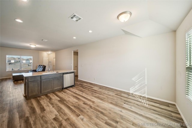 kitchen featuring hardwood / wood-style floors, dark brown cabinetry, an island with sink, sink, and stainless steel dishwasher