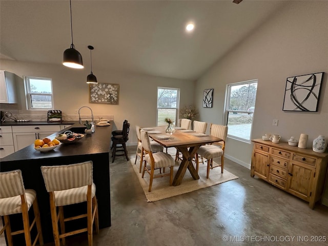 dining room with concrete floors, sink, and vaulted ceiling