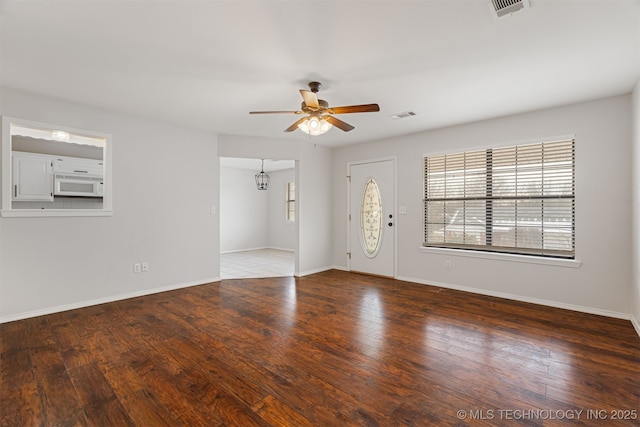 spare room featuring ceiling fan with notable chandelier and dark hardwood / wood-style flooring