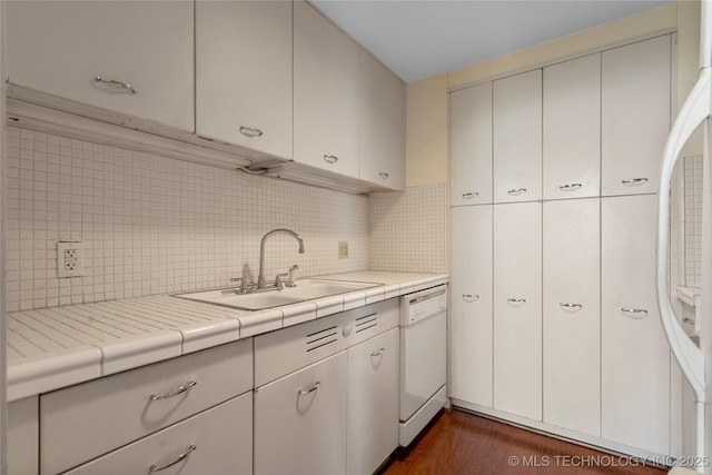 kitchen with dark hardwood / wood-style floors, tile countertops, decorative backsplash, sink, and white dishwasher