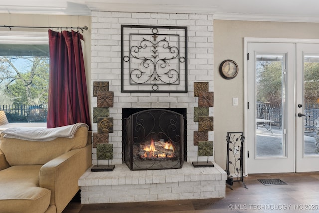 living room featuring ornamental molding, hardwood / wood-style floors, a fireplace, and french doors