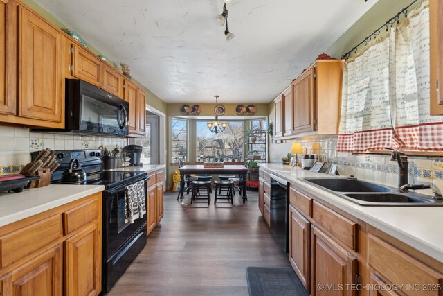 kitchen with pendant lighting, sink, dark hardwood / wood-style flooring, decorative backsplash, and black appliances