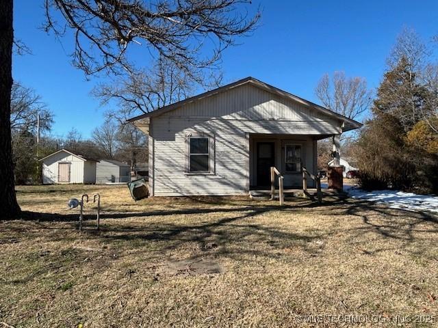 rear view of house featuring a storage shed, covered porch, and a yard