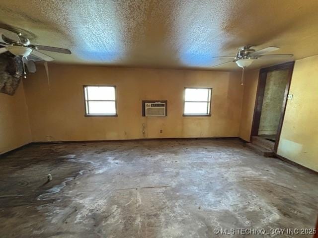 spare room with concrete floors, a textured ceiling, a wall mounted AC, and a healthy amount of sunlight