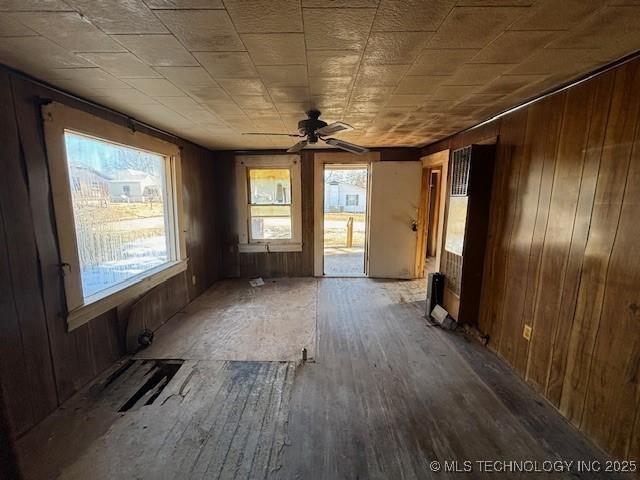 spare room with ceiling fan, wood-type flooring, and wood walls