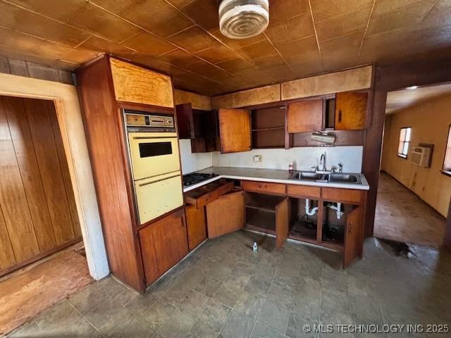 kitchen with multiple ovens, wooden walls, and sink