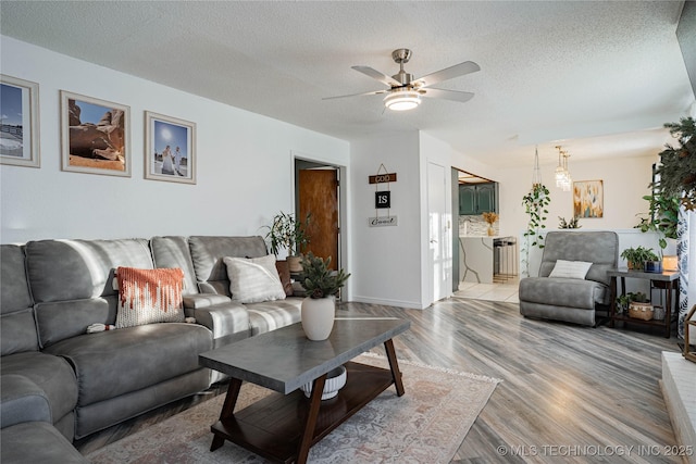 living room with hardwood / wood-style flooring, a textured ceiling, and ceiling fan