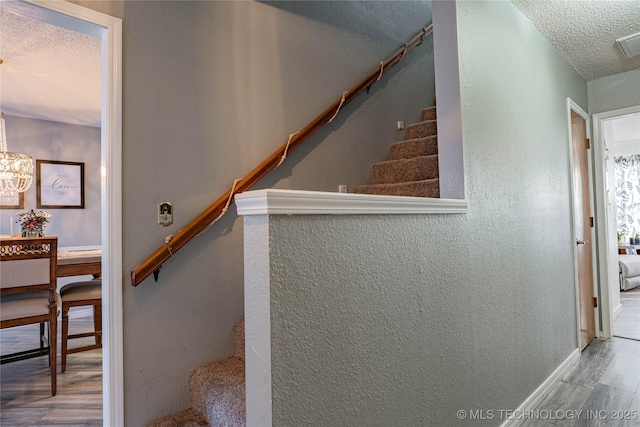 stairway featuring wood-type flooring and a textured ceiling