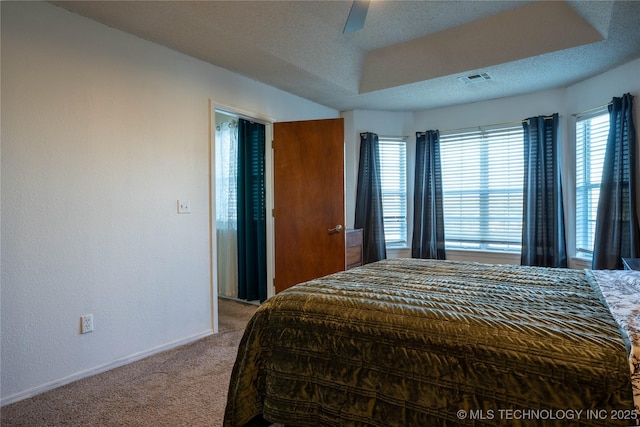 carpeted bedroom with ceiling fan and a tray ceiling