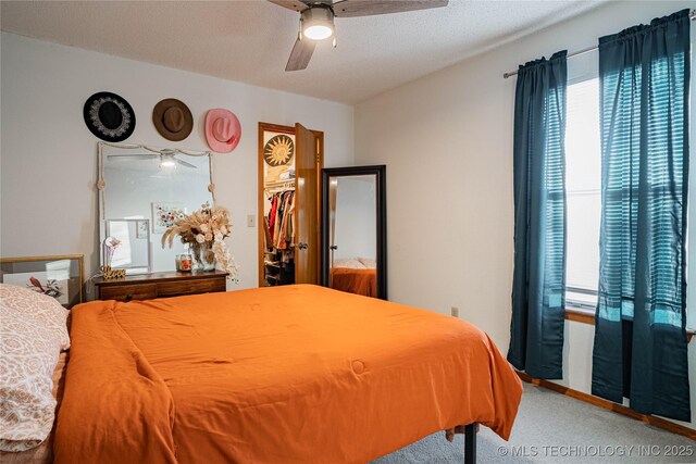 carpeted bedroom featuring ceiling fan, a closet, a spacious closet, and a textured ceiling