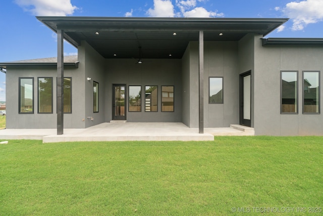 rear view of property with a patio area, a yard, and ceiling fan