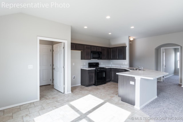 kitchen featuring dark brown cabinetry, black appliances, sink, kitchen peninsula, and a breakfast bar