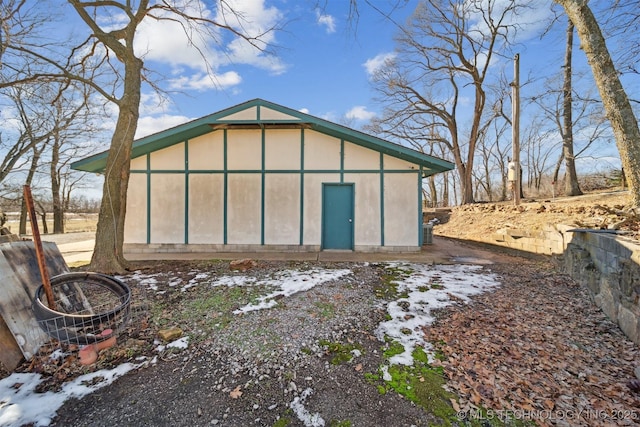 snow covered rear of property with an outdoor structure