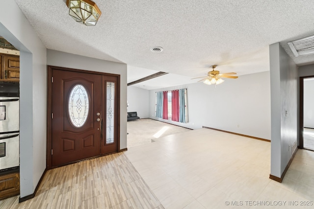 foyer entrance with plenty of natural light, visible vents, a textured ceiling, and ceiling fan