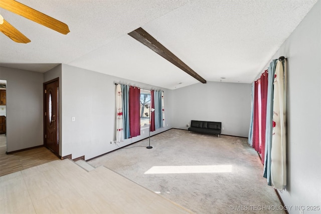 spare room with light carpet, ceiling fan, a textured ceiling, and vaulted ceiling with beams