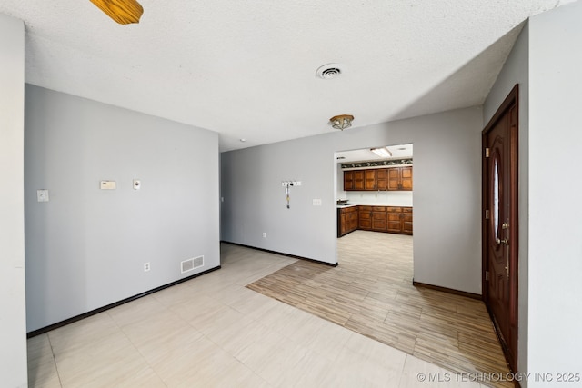 unfurnished room featuring visible vents, baseboards, and a textured ceiling