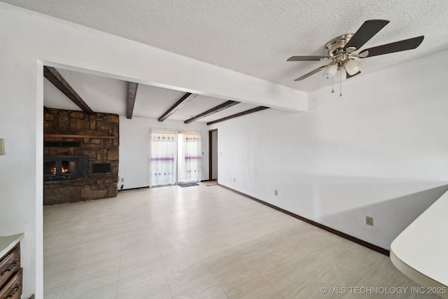unfurnished living room featuring beamed ceiling, a textured ceiling, a stone fireplace, baseboards, and ceiling fan