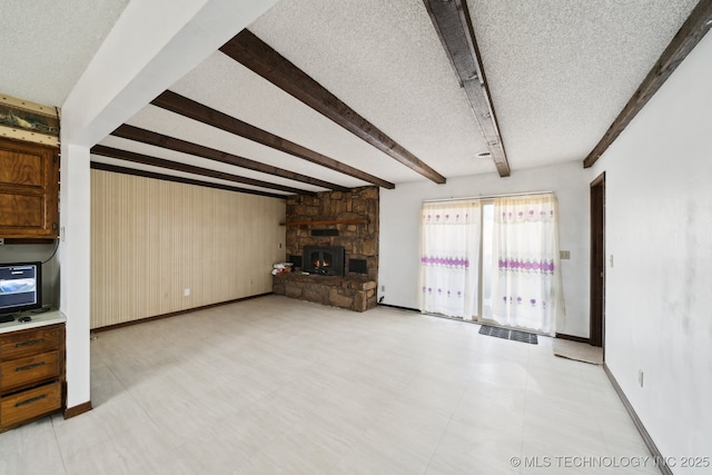 unfurnished living room featuring beamed ceiling, a fireplace, a textured ceiling, and baseboards