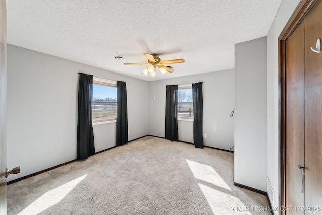 unfurnished bedroom with a textured ceiling, ceiling fan, baseboards, and light carpet