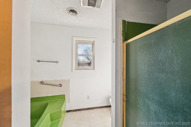full bath with toilet, a bath, visible vents, and a textured ceiling