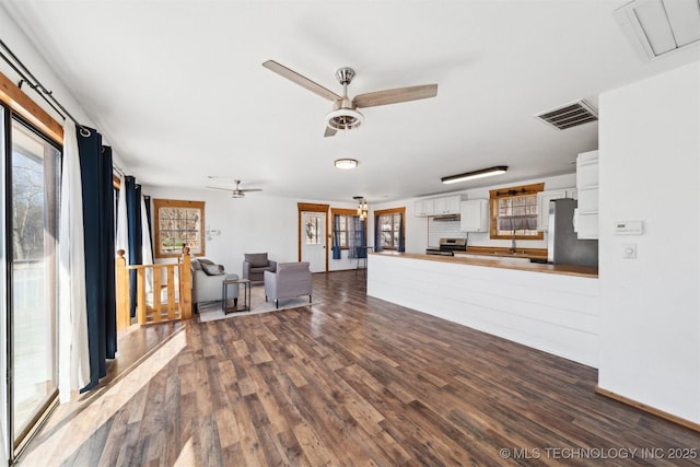 unfurnished living room featuring ceiling fan and dark hardwood / wood-style floors