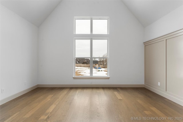 additional living space with high vaulted ceiling, baseboards, and wood finished floors