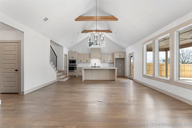 unfurnished living room with a chandelier, light wood-style flooring, a sink, high vaulted ceiling, and stairs