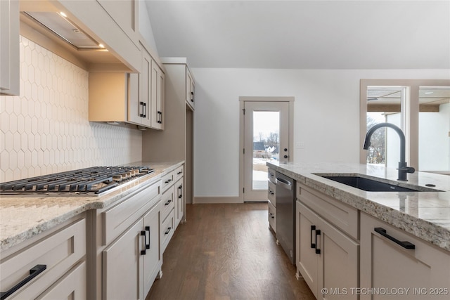 kitchen featuring light stone counters, stainless steel appliances, a sink, white cabinetry, and tasteful backsplash