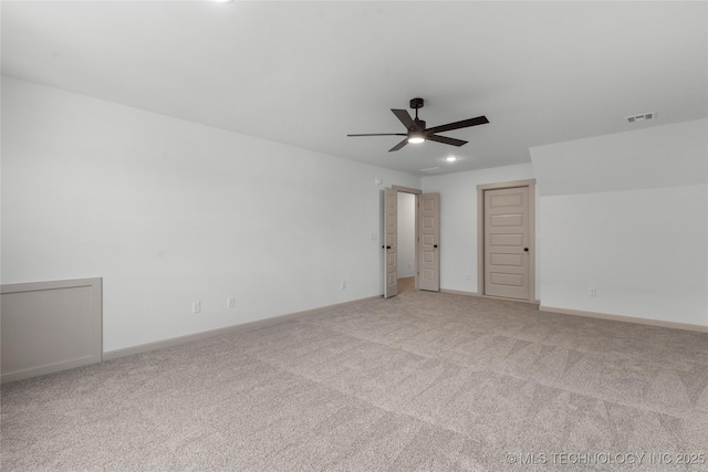 spare room featuring light carpet, ceiling fan, visible vents, and baseboards