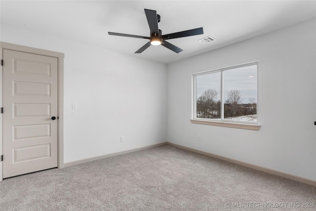 spare room with light carpet, baseboards, visible vents, and a ceiling fan